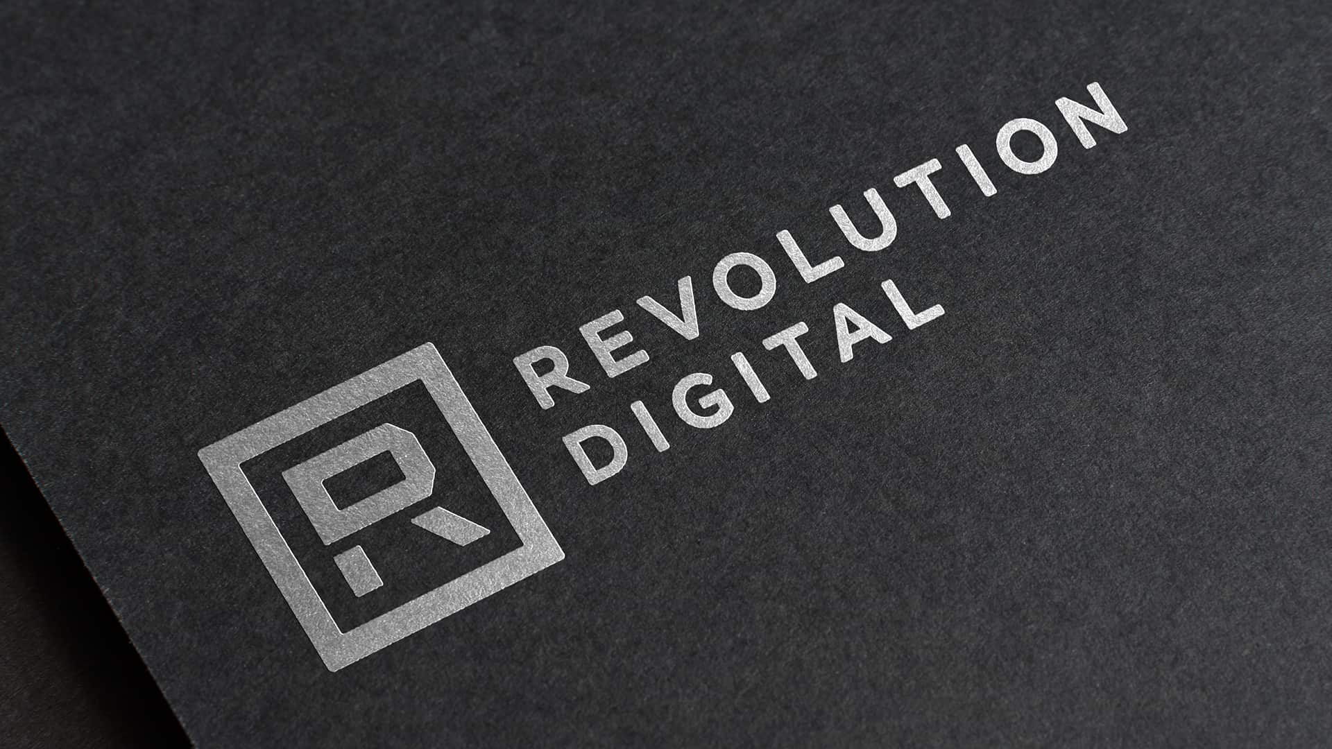 revolution digital logo embossed in silver on black paper