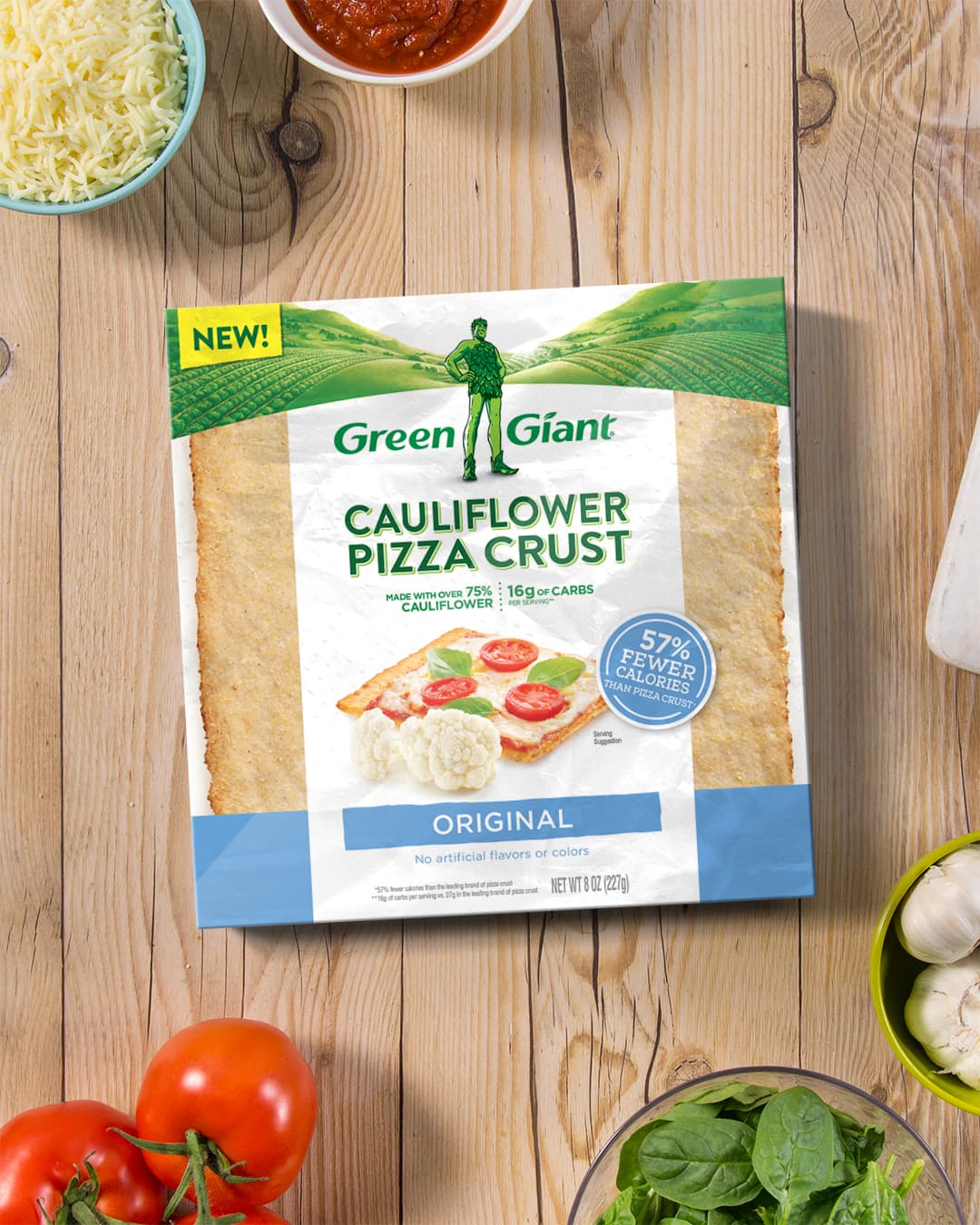 green giant cauliflower pizza box on wood background surrounded by ingredients