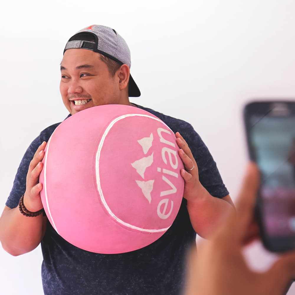 happy tennis fan holding an oversized evian tennis ball